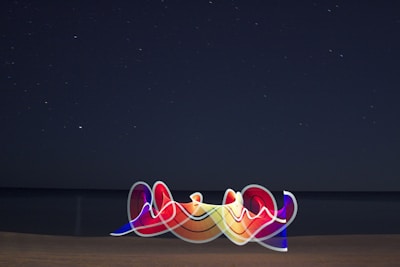 A glowing neon pastel illustration of a celestial compass over ocean waves under a starry sky.