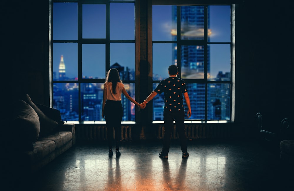 Mann und Frau halten Händchen vor Glasfenster