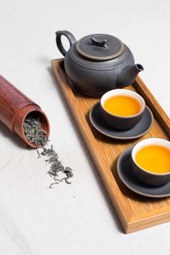 A wooden barrel filled with tea leaves, with a tea cup beside it containing tea