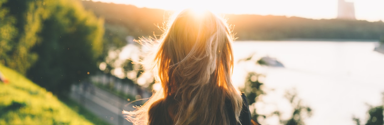 woman sitting while looking at the sunset