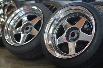 Close-up of a shiny alloy wheel and new tyre stacked in a workshop.