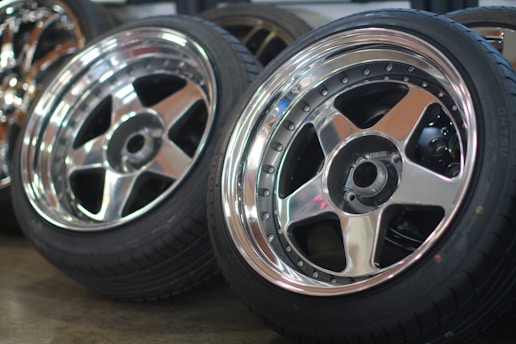 Close-up of a shiny alloy wheel and new tyre stacked in a workshop.