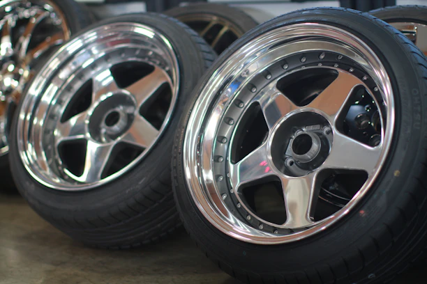 Close-up of sleek black alloy wheels stacked in a modern warehouse.