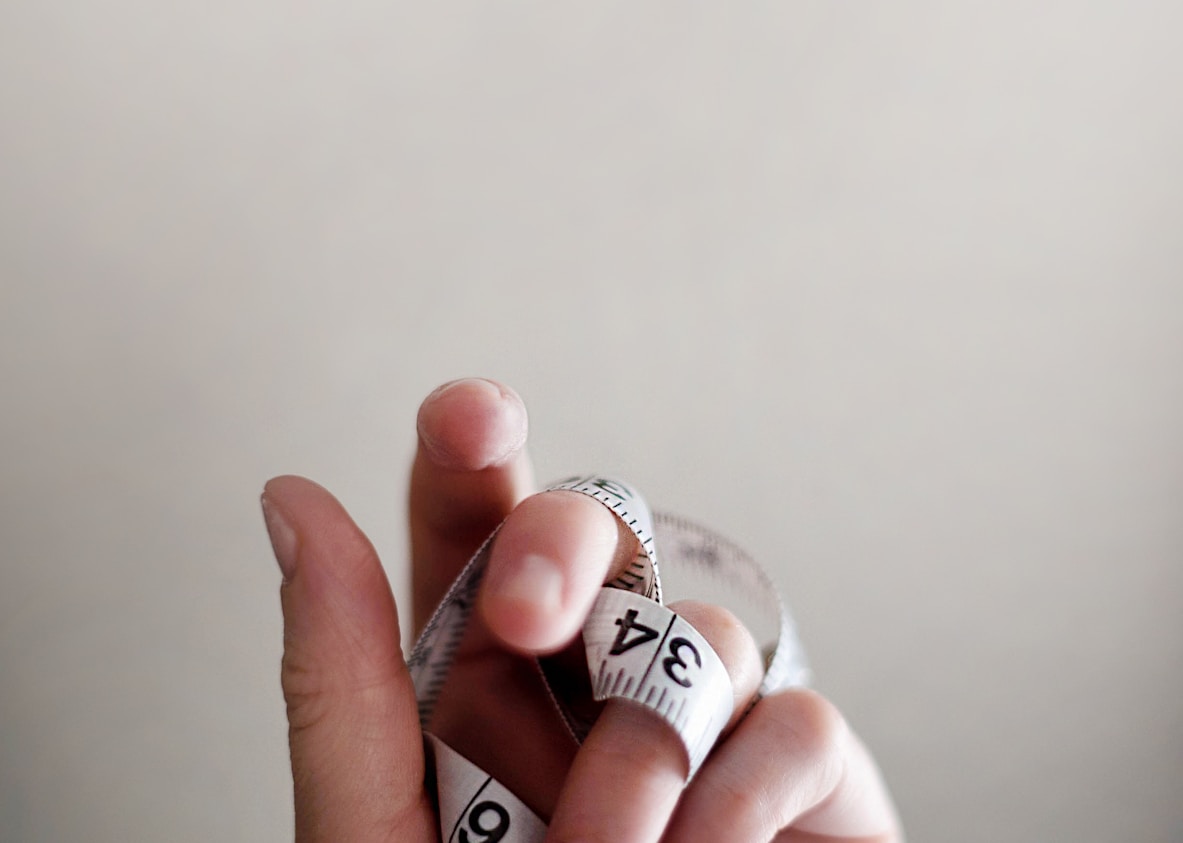 person's left hand wrapped by tape measure