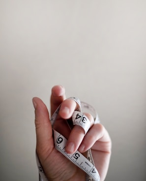 person's left hand wrapped by tape measure