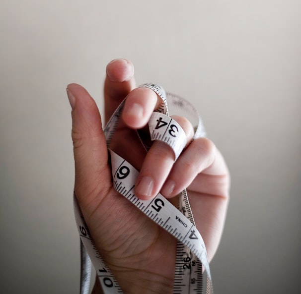 person's left hand wrapped by tape measure