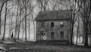 A suspenseful horror game setting with a shadowy abandoned mansion surrounded by fog and twisted trees.