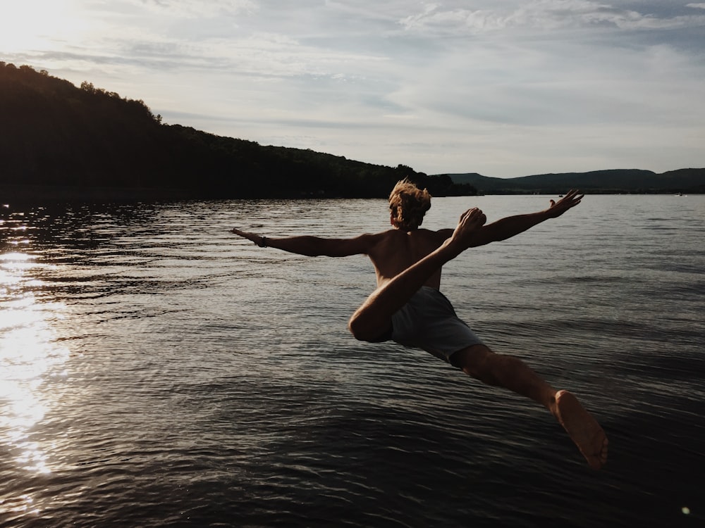 person jumping to body of water