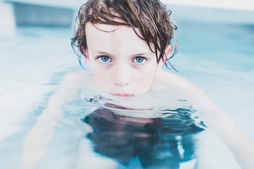 Selektive Fokusfotografie eines Jungen, der auf dem Wasser schwimmt
