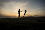 A sunset silhouette of the couple holding hands together.