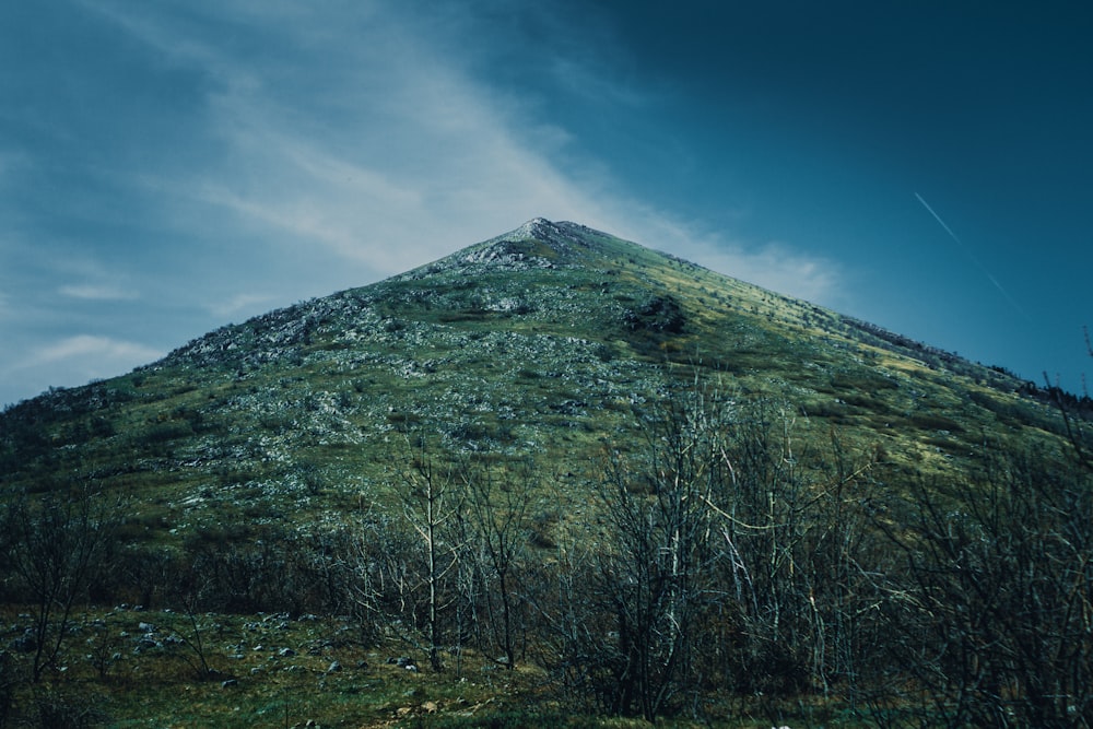 a very tall green mountain with a sky background