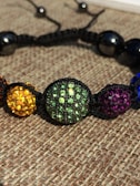 A close-up of hands holding a colorful beaded bracelet.