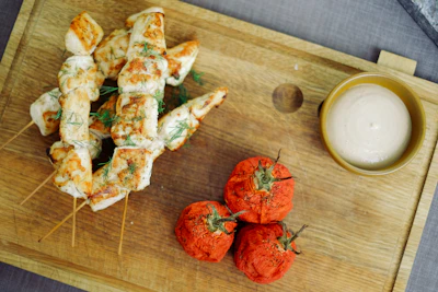 Freshly grilled chicken skewers with a slight char resting on rustic wooden board