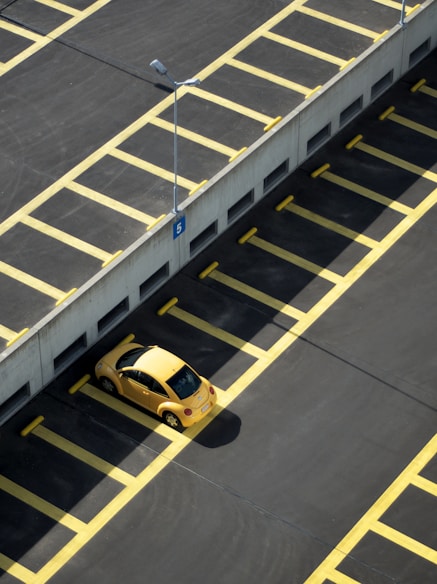 yellow coupe on parking lot at daytime