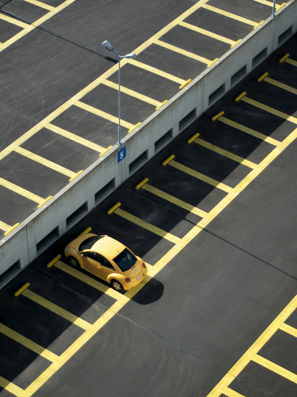 昼間の駐車場に黄色いクーペ