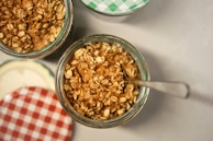 Close-up of healthy snack mixes in clear glass jars with fresh ingredients around.
