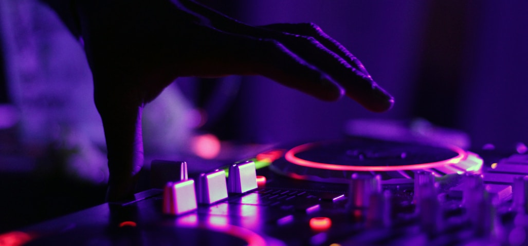 selective focus silhouette photography of man playing red-lighted DJ terminal