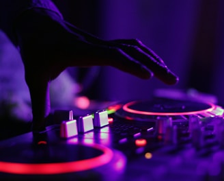 selective focus silhouette photography of man playing red-lighted DJ terminal