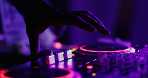 selective focus silhouette photography of man playing red-lighted DJ terminal