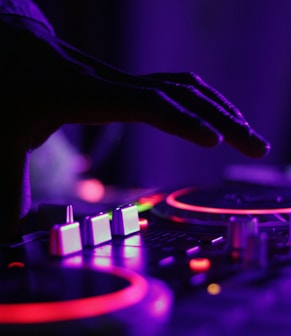 selective focus silhouette photography of man playing red-lighted DJ terminal