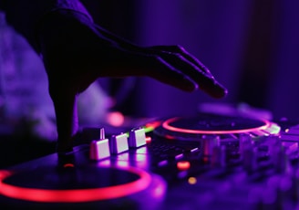 selective focus silhouette photography of man playing red-lighted DJ terminal