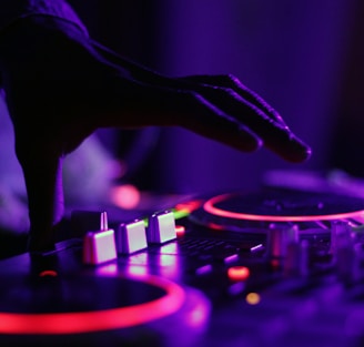 selective focus silhouette photography of man playing red-lighted DJ terminal