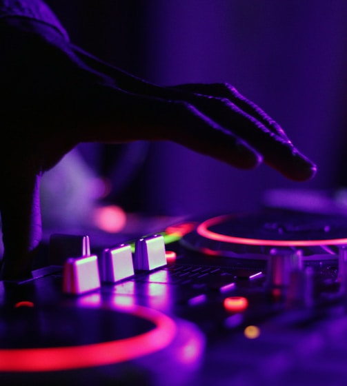 selective focus silhouette photography of man playing red-lighted DJ terminal