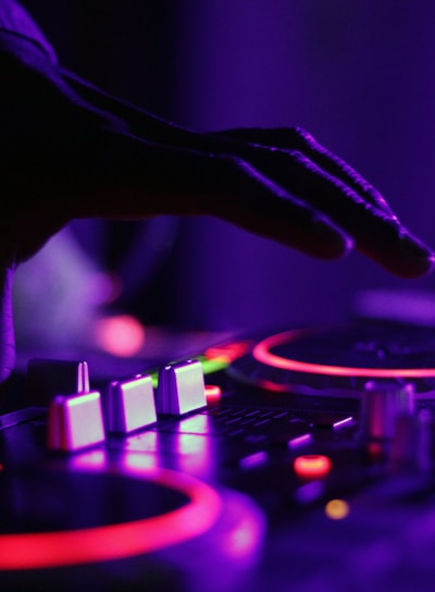 selective focus silhouette photography of man playing red-lighted DJ terminal