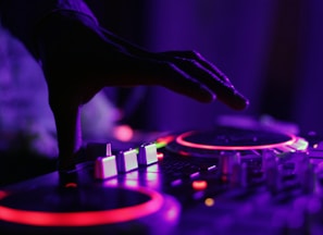 selective focus silhouette photography of man playing red-lighted DJ terminal