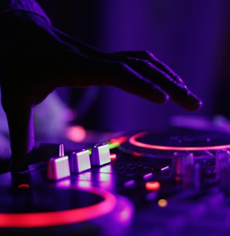 selective focus silhouette photography of man playing red-lighted DJ terminal