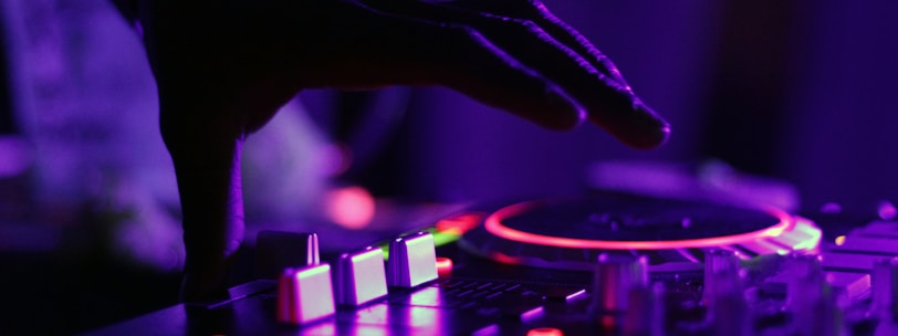 selective focus silhouette photography of man playing red-lighted DJ terminal