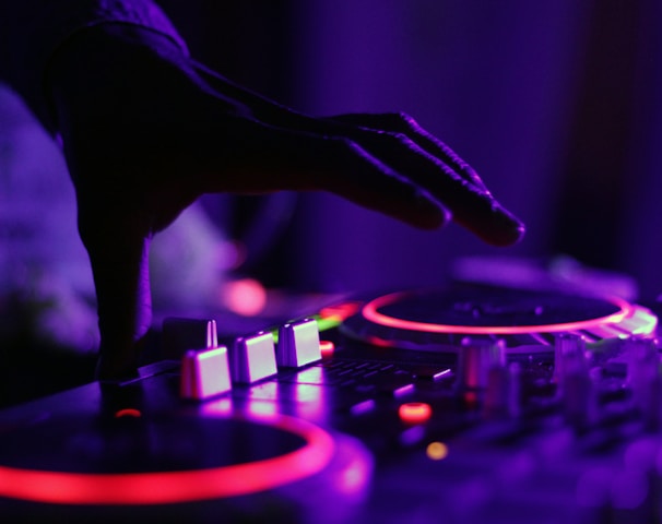 selective focus silhouette photography of man playing red-lighted DJ terminal