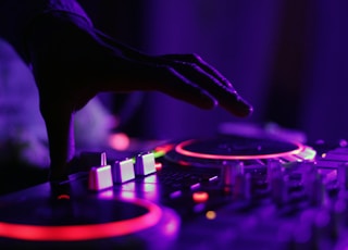 selective focus silhouette photography of man playing red-lighted DJ terminal