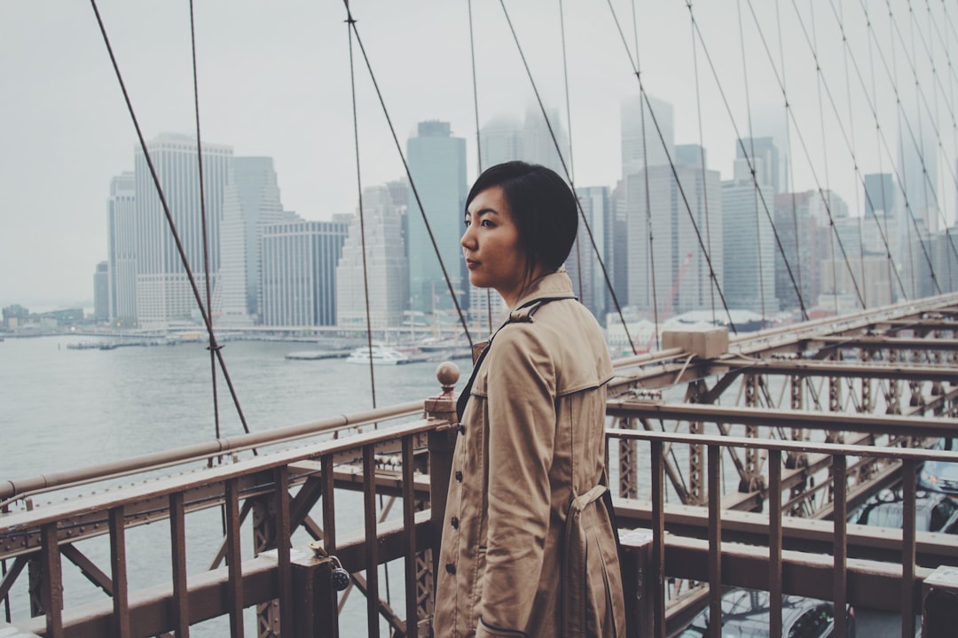 woman standing on bridge railings at daytime