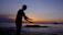 Peaceful seaside view with a person practicing Qigong at sunrise.