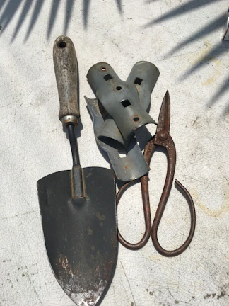 A set of garden tools with razor-sharp edges resting on a wooden bench.