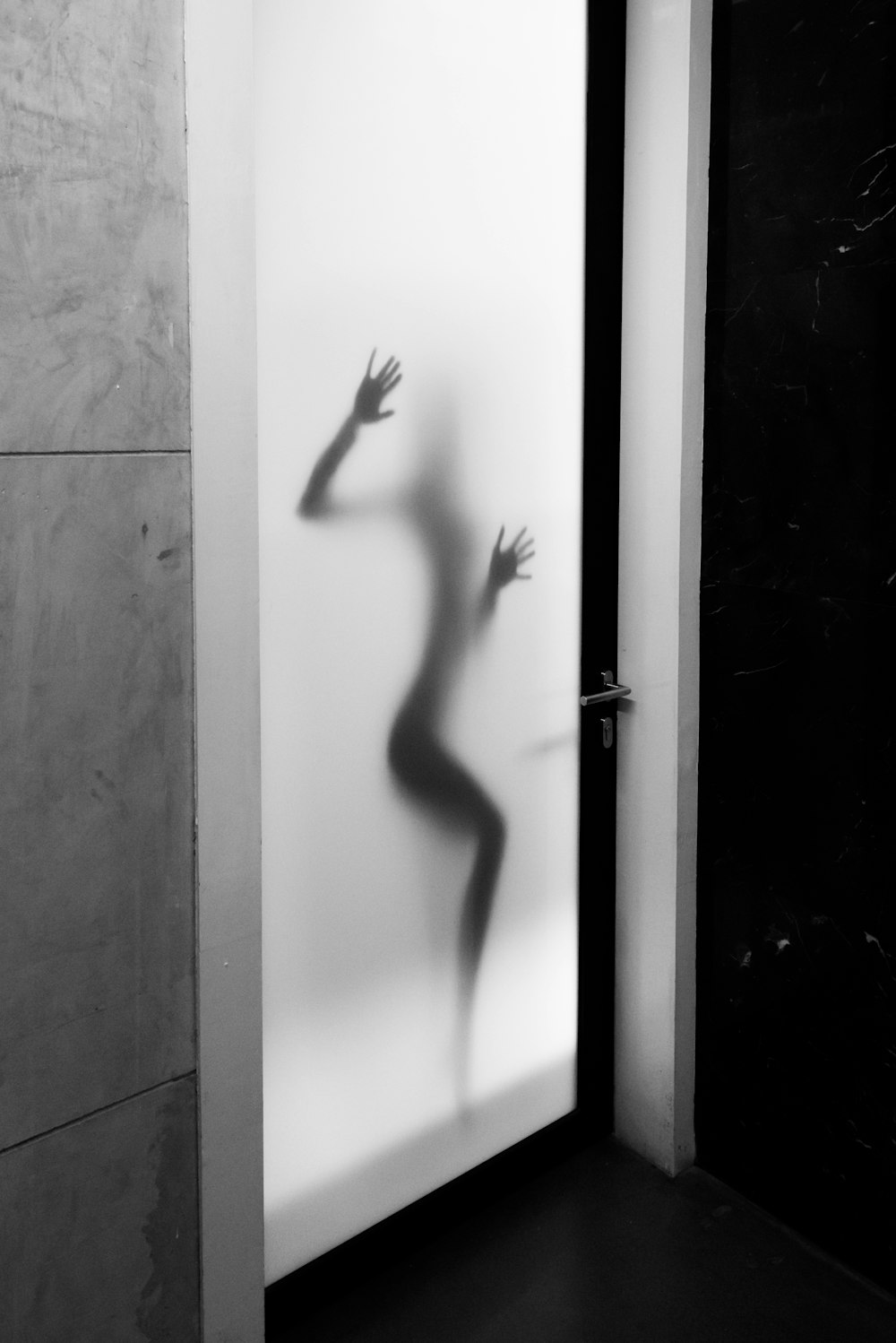 sombra da pessoa contra a porta de vidro do painel branco