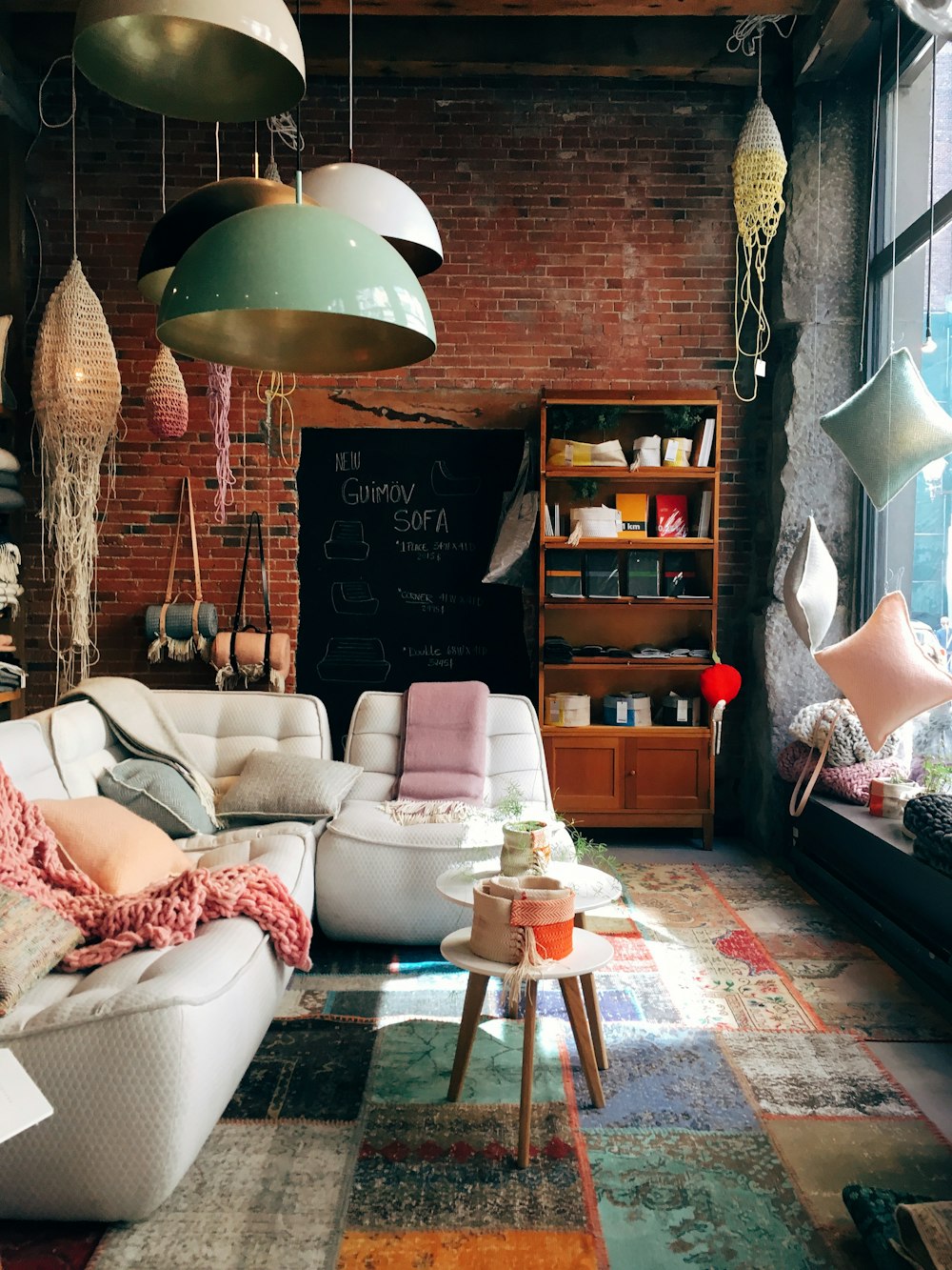 A living room having a brick wall, glass windows and containing a white sofa with throw pillows in Canada.