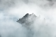 A misty mountain peak emerging through early morning fog.