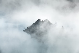 A misty mountain peak emerging through early morning fog.