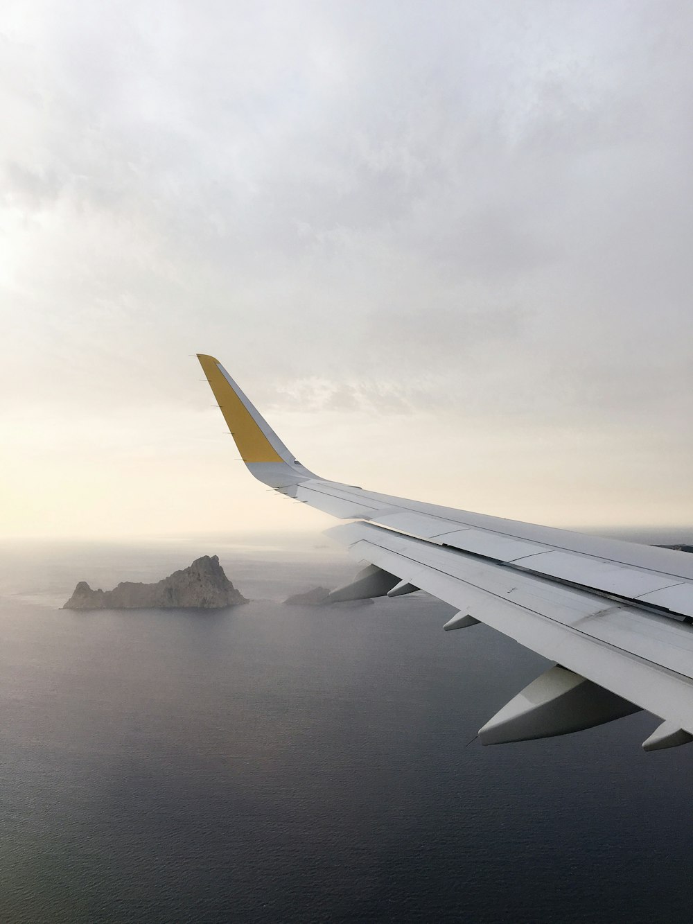 aile d’avion au-dessus d’un plan d’eau pendant la journée