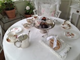 A beautifully set high-tea table with elegant teacups and pastries.