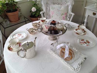 A beautifully set high-tea table with elegant teacups and pastries.