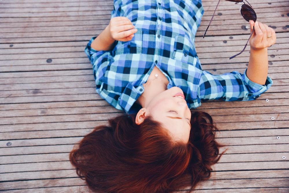 woman in blue flannel shirt laying on floor