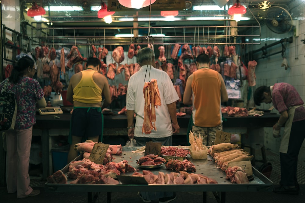 Étalage de viande crue derrière cinq personnes