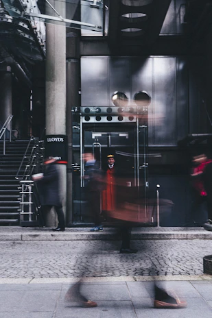 Uniformed doorman greeting guests at a stylish building entrance during an evening event.