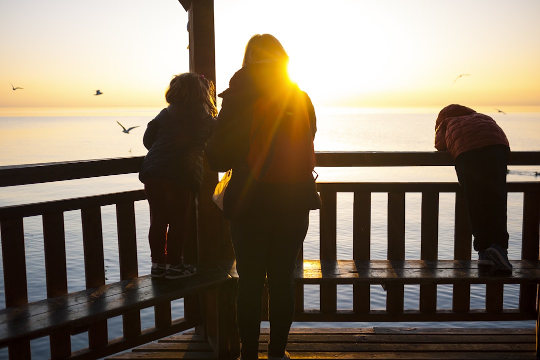 person near on brown wooden fence, A mother and her children on a pier