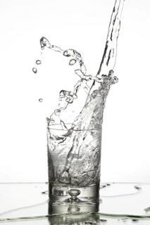 Refreshing splash of mineral water pouring into a crystal-clear glass with droplets in motion.