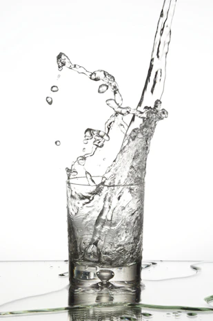 Refreshing splash of mineral water pouring into a crystal-clear glass with droplets in motion.