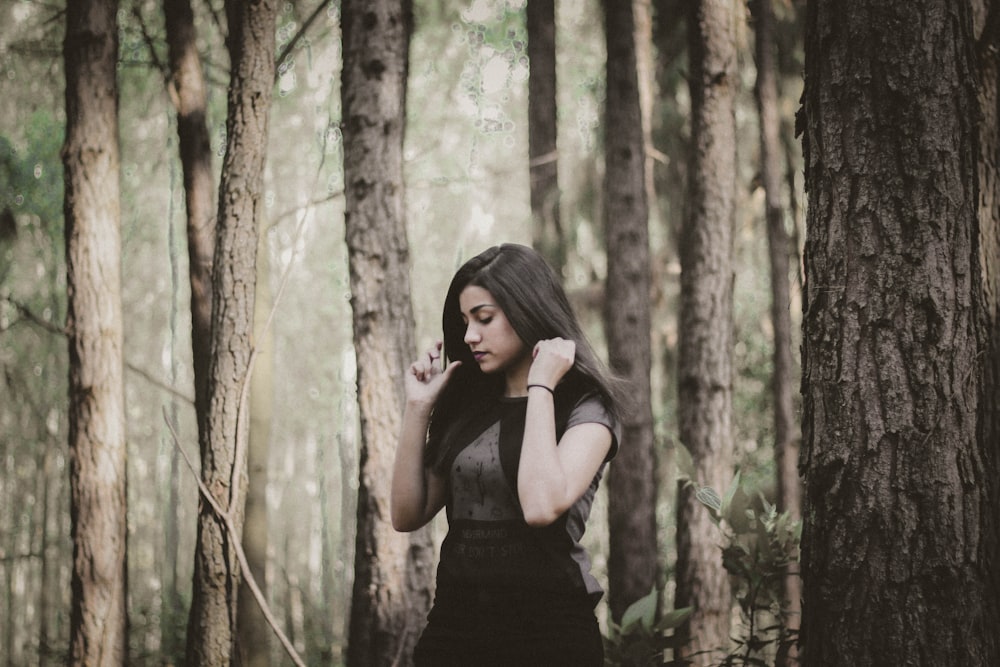 a woman standing in a forest talking on a cell phone